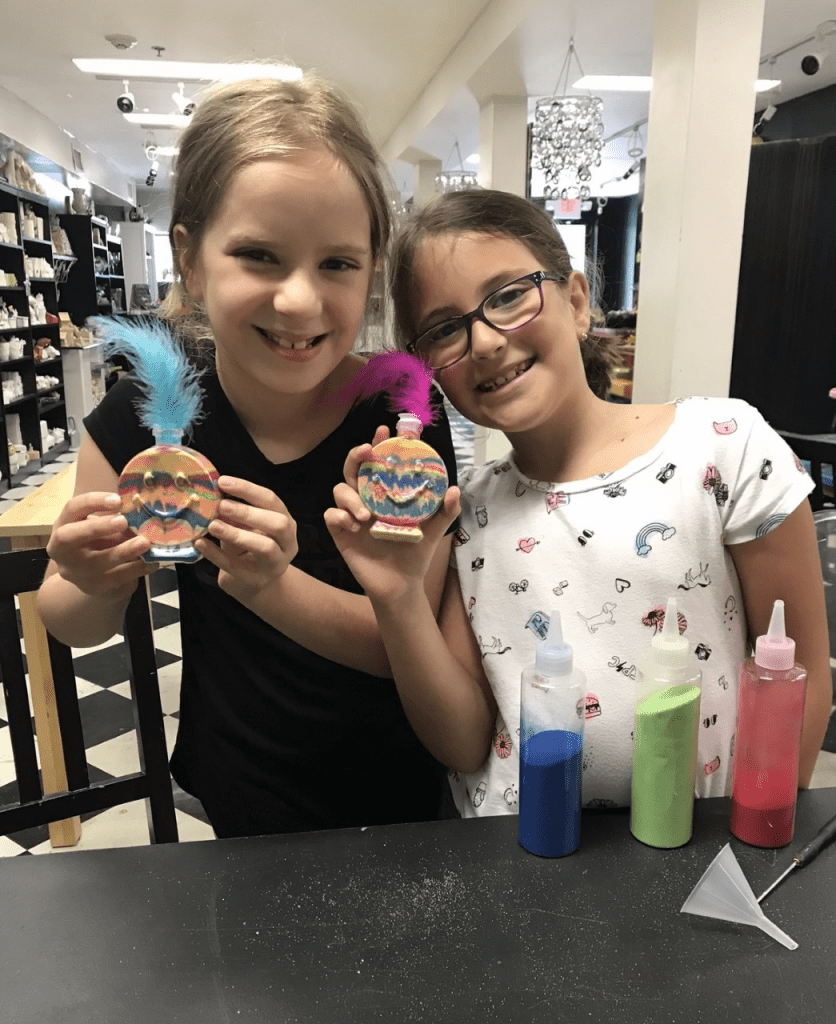 Happy children proudly showing finished pottery painting and clay art projects in Englewood NJ